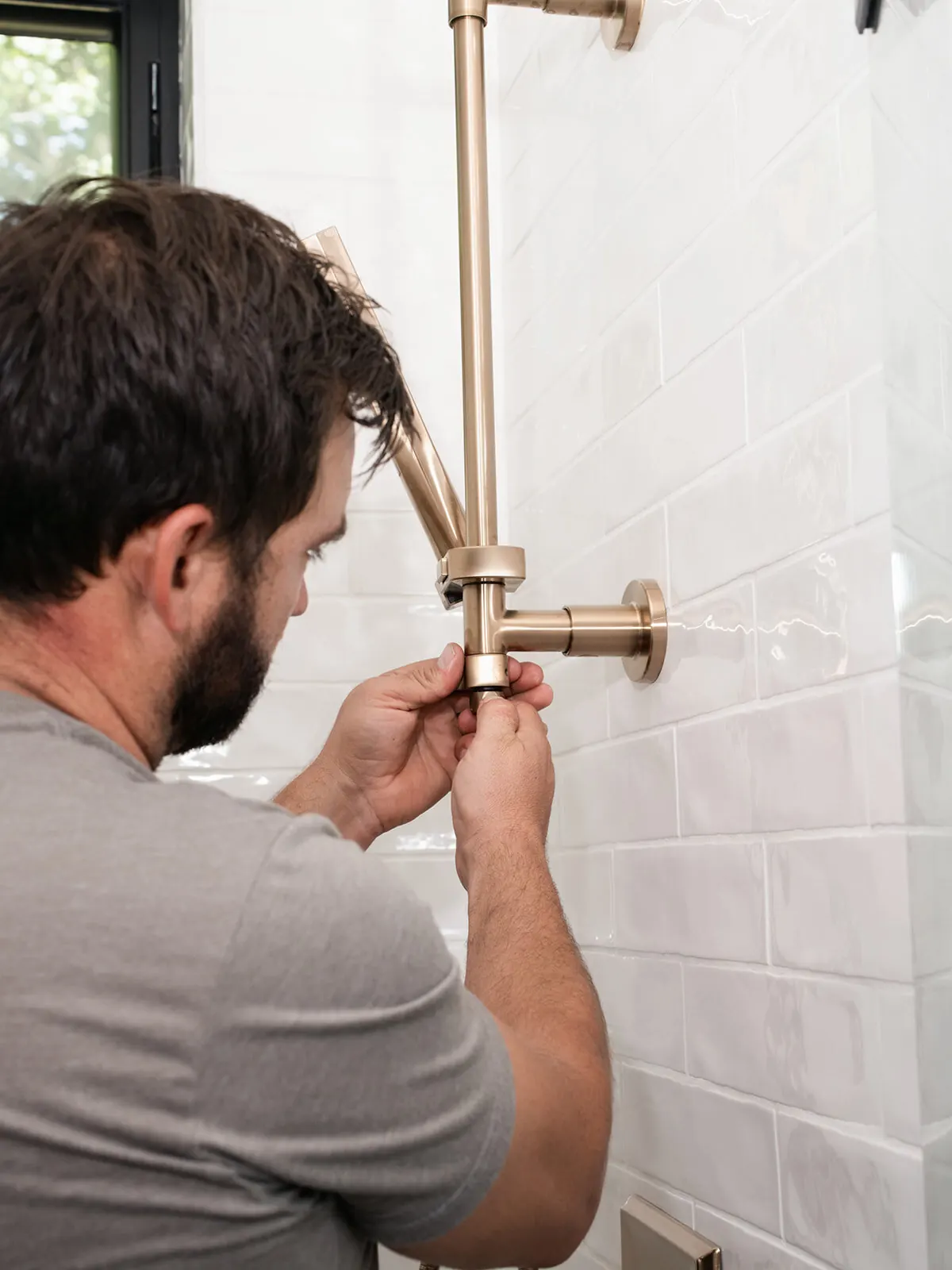 Luke Williams fitting a brushed brass shower valve during a bathroom remodel