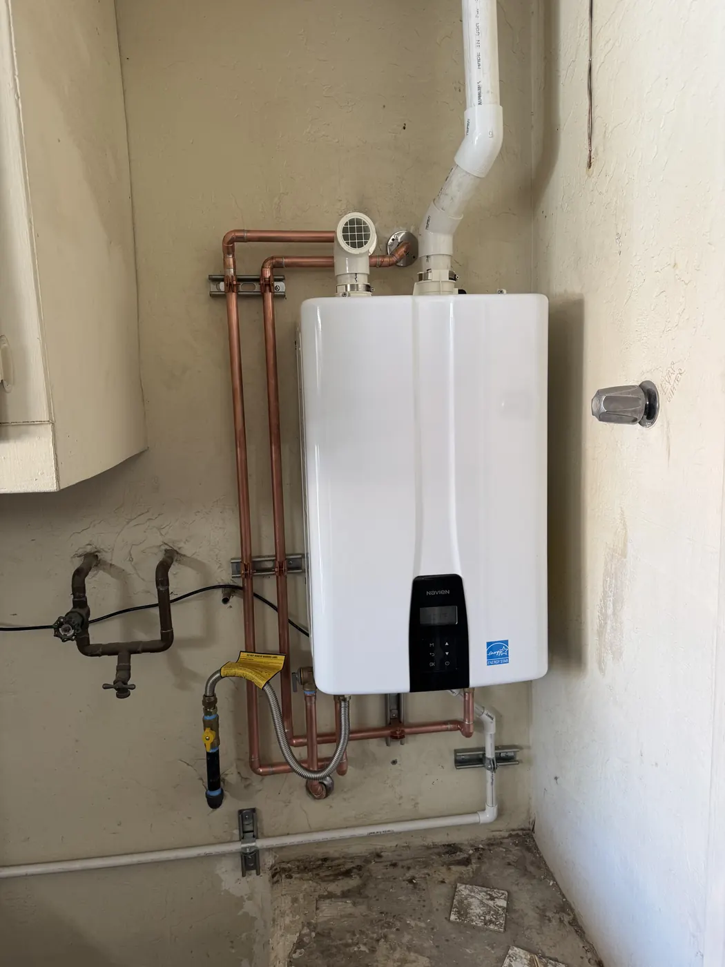 Wall-mounted tankless water heater with copper water lines in a Tempe laundry room
