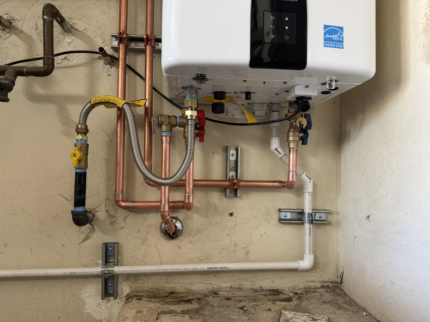 Close view of copper water lines, gas connection and isolation valves under a tankless water heater in Tempe
